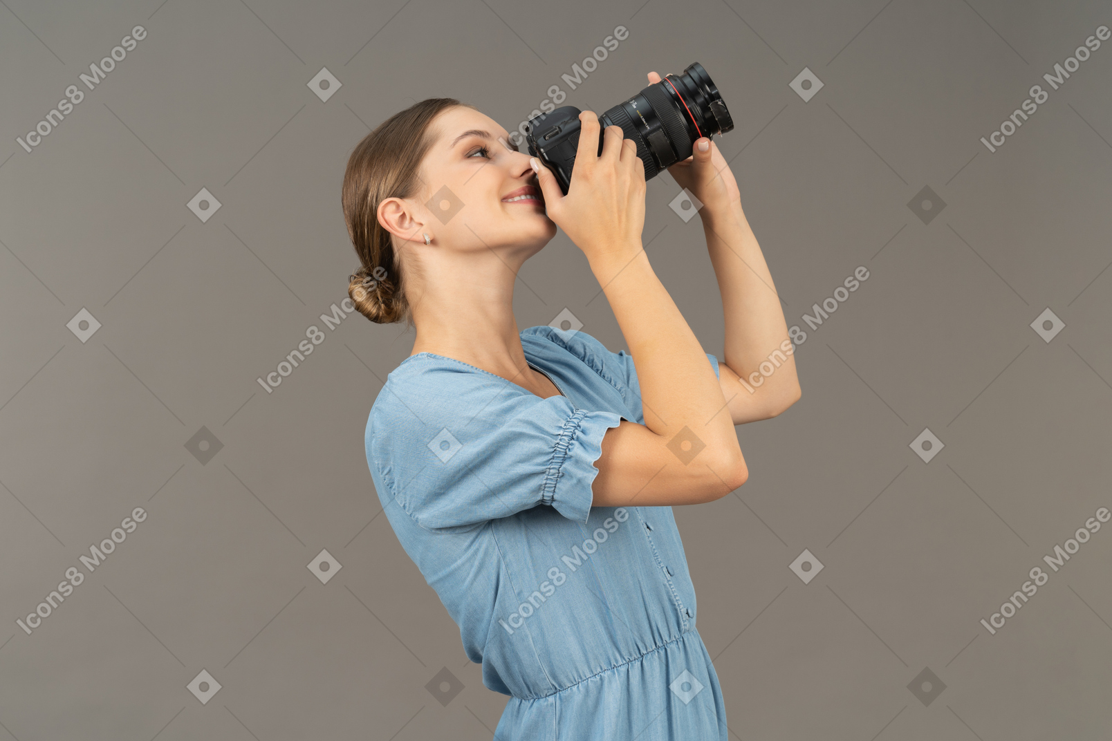 Трехчетвертный вид улыбающейся молодой женщины в синем платье, делающей выстрел