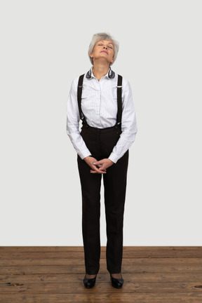 Front view of an old tired female in office clothes grimacing holding hands together