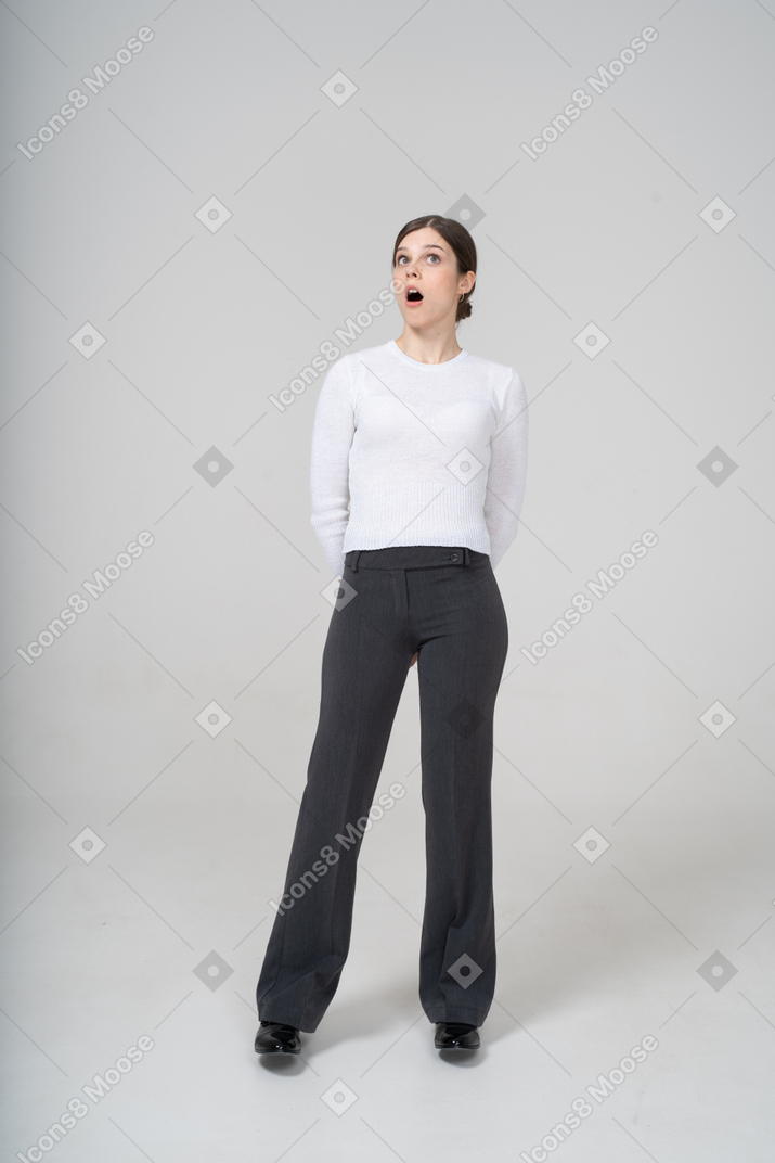 Вид спереди впечатленной женщины в белой блузке и черных брюках