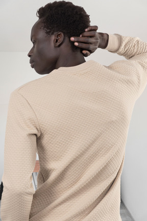 A man in a tan sweater scratching his head
