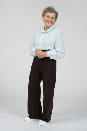Вид в три четверти на пожилую женщину, ярко улыбающуюся со сложенными руками
