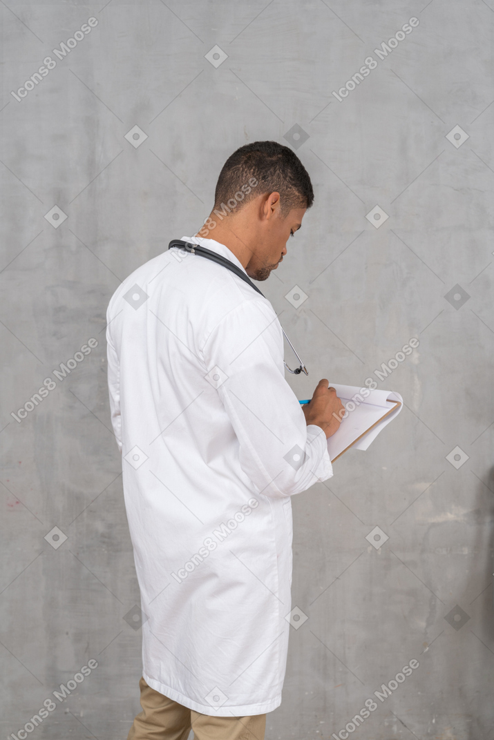 Vista posteriore di un medico maschio che prende appunti