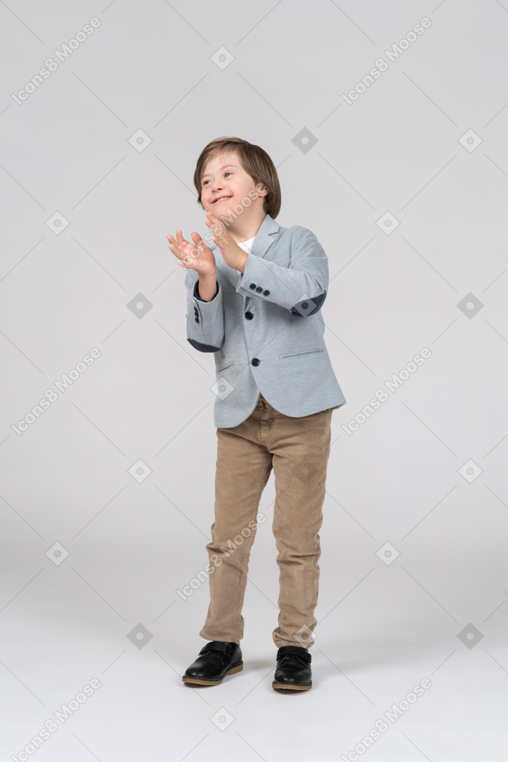 Boy in a blue jacket and khaki pants clapping his hands
