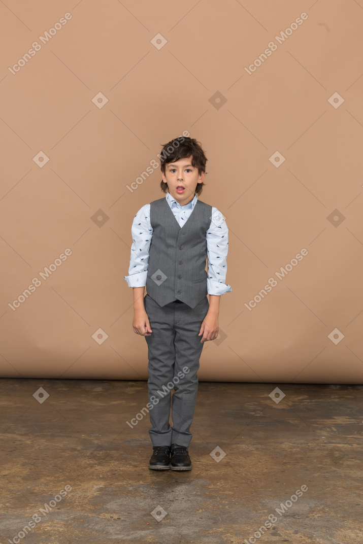 一个穿着灰色西装的印象深刻的男孩的前视图