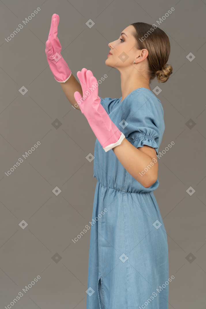 Side view of a young woman raising her hands while wearing gloves
