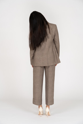 Vista posteriore di una giovane donna in tailleur marrone inclinando la testa
