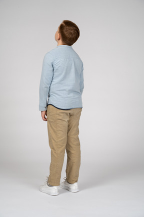 Вид сзади мальчика в повседневной одежде, смотрящего вверх