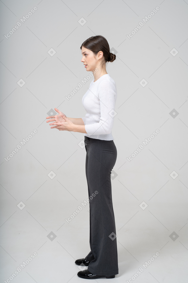 Side view of a woman in black pants and white shirt gesturing