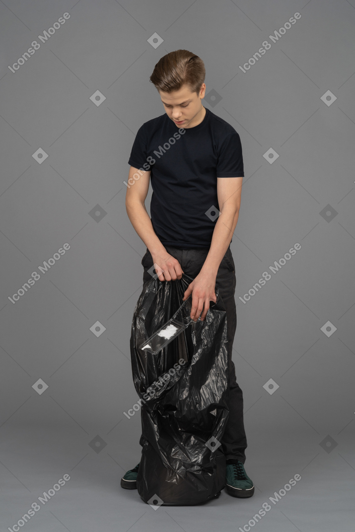 A young man filling a trash bag