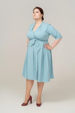 Front view of a woman in blue dress posing with hands on hips