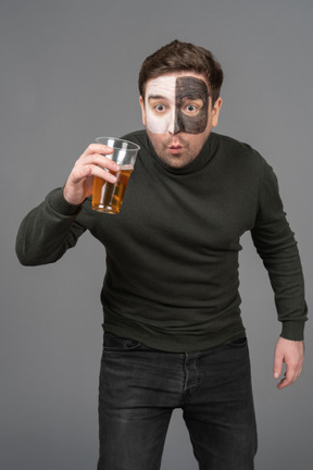 Front view of a surprised male football fan holding a beer