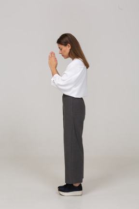 Vista posteriore di tre quarti di una giovane donna in preghiera in abiti da ufficio che si tiene per mano insieme