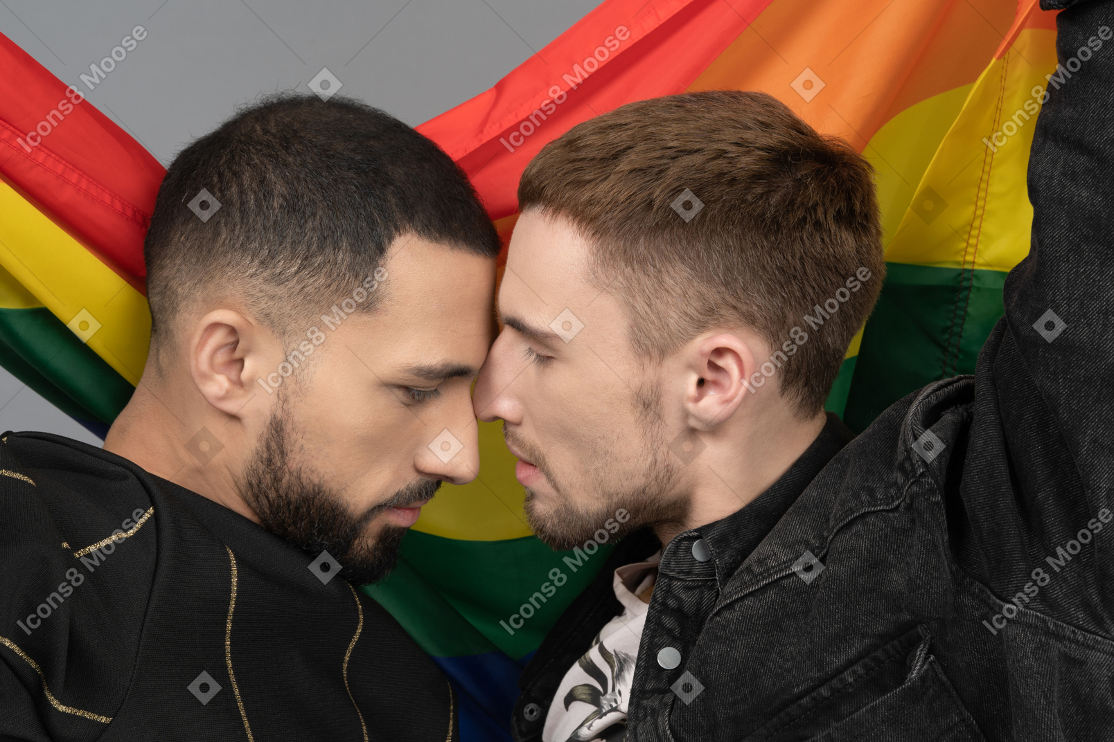Close-up of two young men touching noses sensually in front of lgbt flag