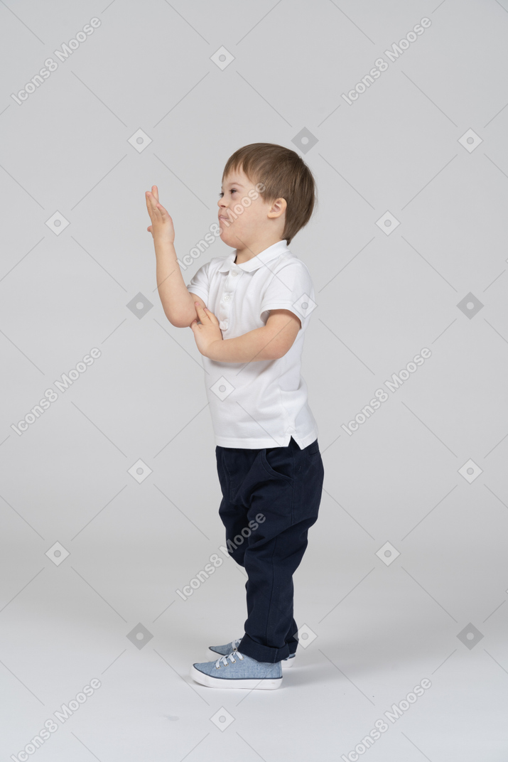 Vista lateral do menino levantando a mão