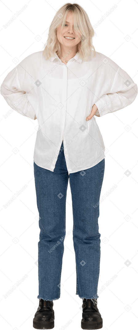 Vista frontale di una donna bionda in abiti casual, mettendo le mani sui fianchi e sorridente