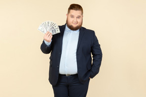 A plus-size man in a black costume with dollar bills in his hands