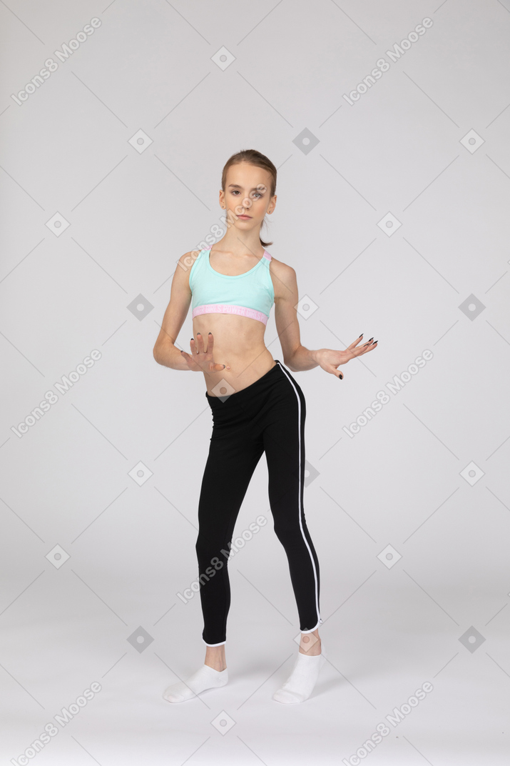 Vista frontal de una jovencita en ropa deportiva bailando mientras gesticula