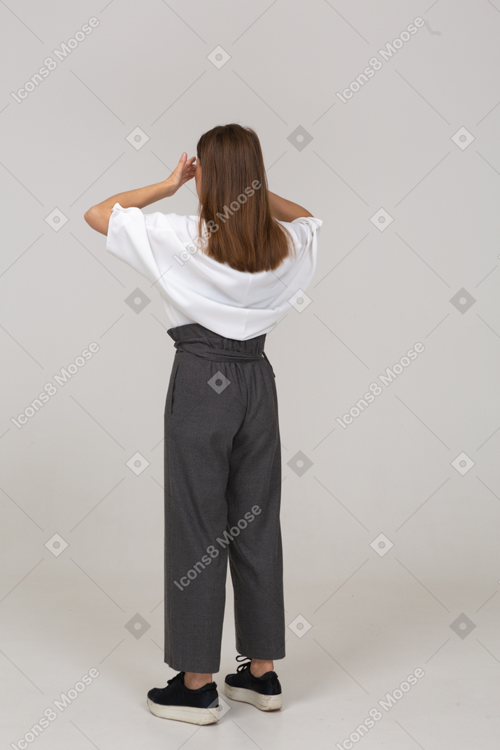 Vista posterior de tres cuartos de una joven en ropa de oficina cerrando los ojos