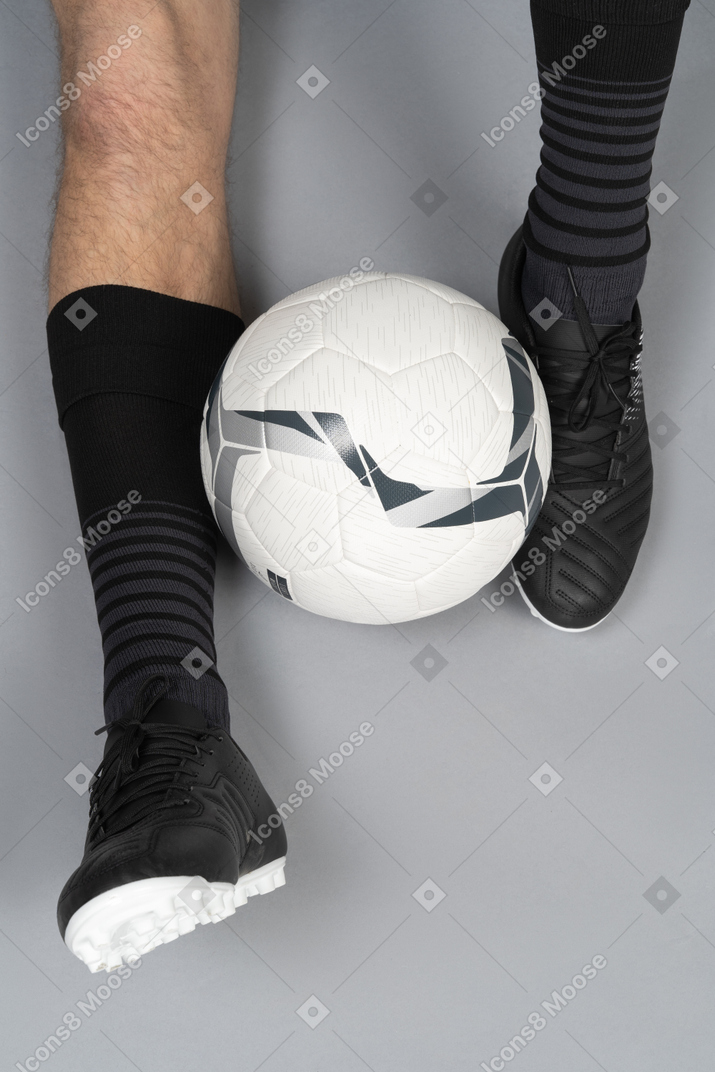 Close-up of a football player sitting with a ball