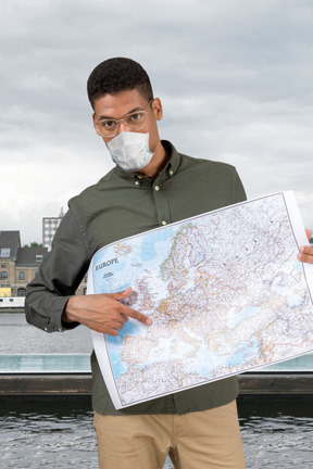 A man wearing a face mask holding a map