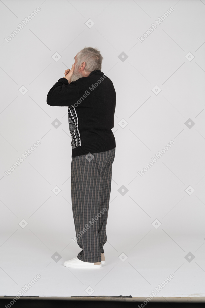 Rear view of old man with hands covering mouth