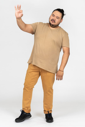 Plump asian man keeping his eyes closed and making ok gesture
