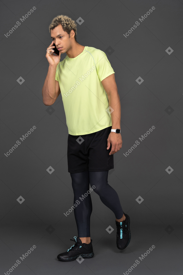 Side view of a dark-skinned young man having a phone call