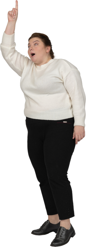 Side view of a plus size woman in casual clothes pointing up