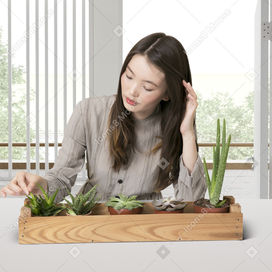 A woman sitting at a table with succulents in a tray