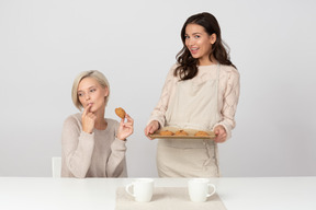 Young woman offering homemade cookies to her friend