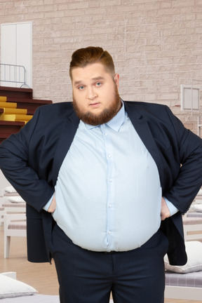 A fat man in a suit standing in a basketball court with beds