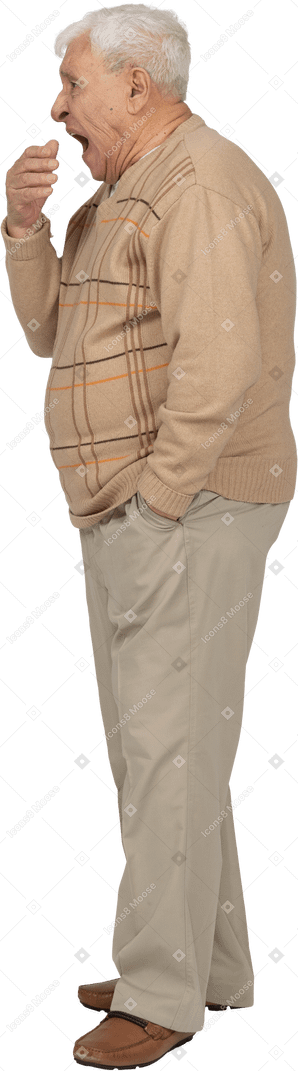 Side view of an old man in casual clothes yawning