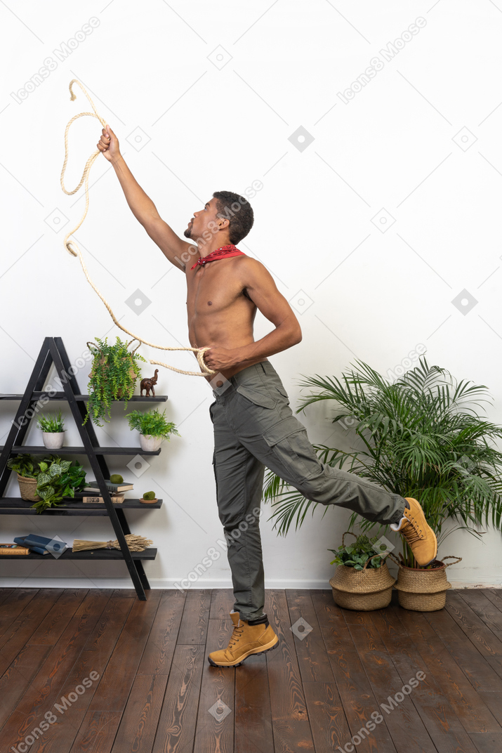 Side view of athletic man outstretching his arm and throwing a lasso