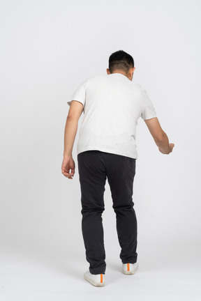 Rear view of a man bending down with extended arm