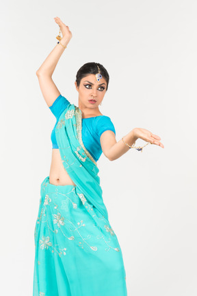 Giovane donna indiana in sari blu in piedi in posizione di danza