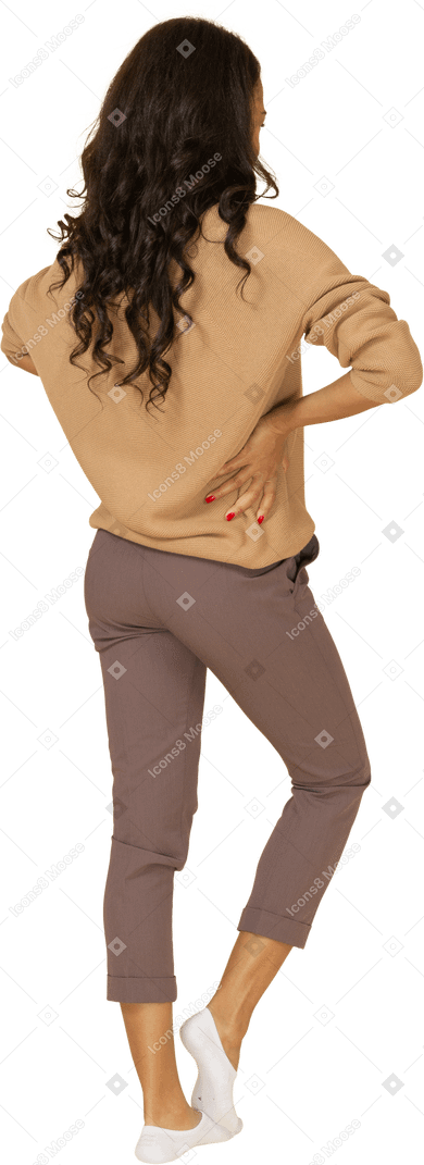 腰に手を置いている浅黒い肌の陽気な若い女性の4分の3の背面図