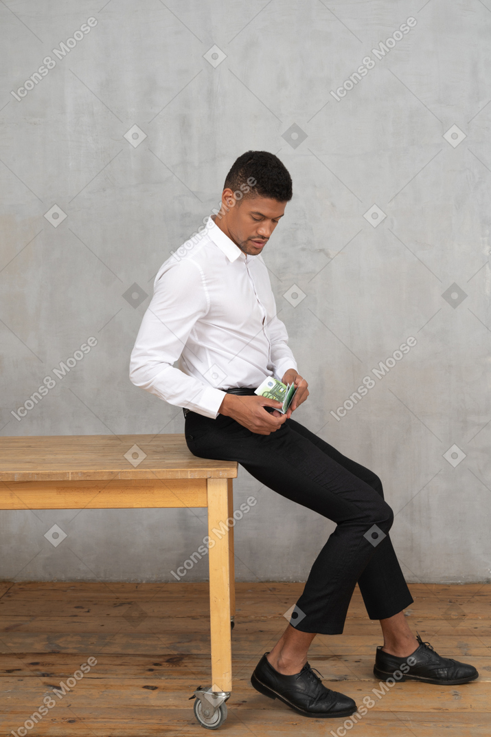 Homem bem vestido contando dinheiro enquanto está sentado em uma mesa