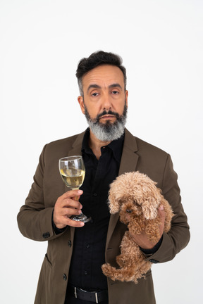 Homem maduro, segurando um cachorro e um copo de vinho