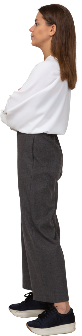 Vista lateral de uma jovem descontente com roupas de escritório, cruzando os braços
