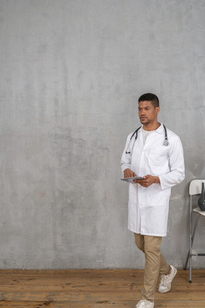 Male doctor with tablet walking