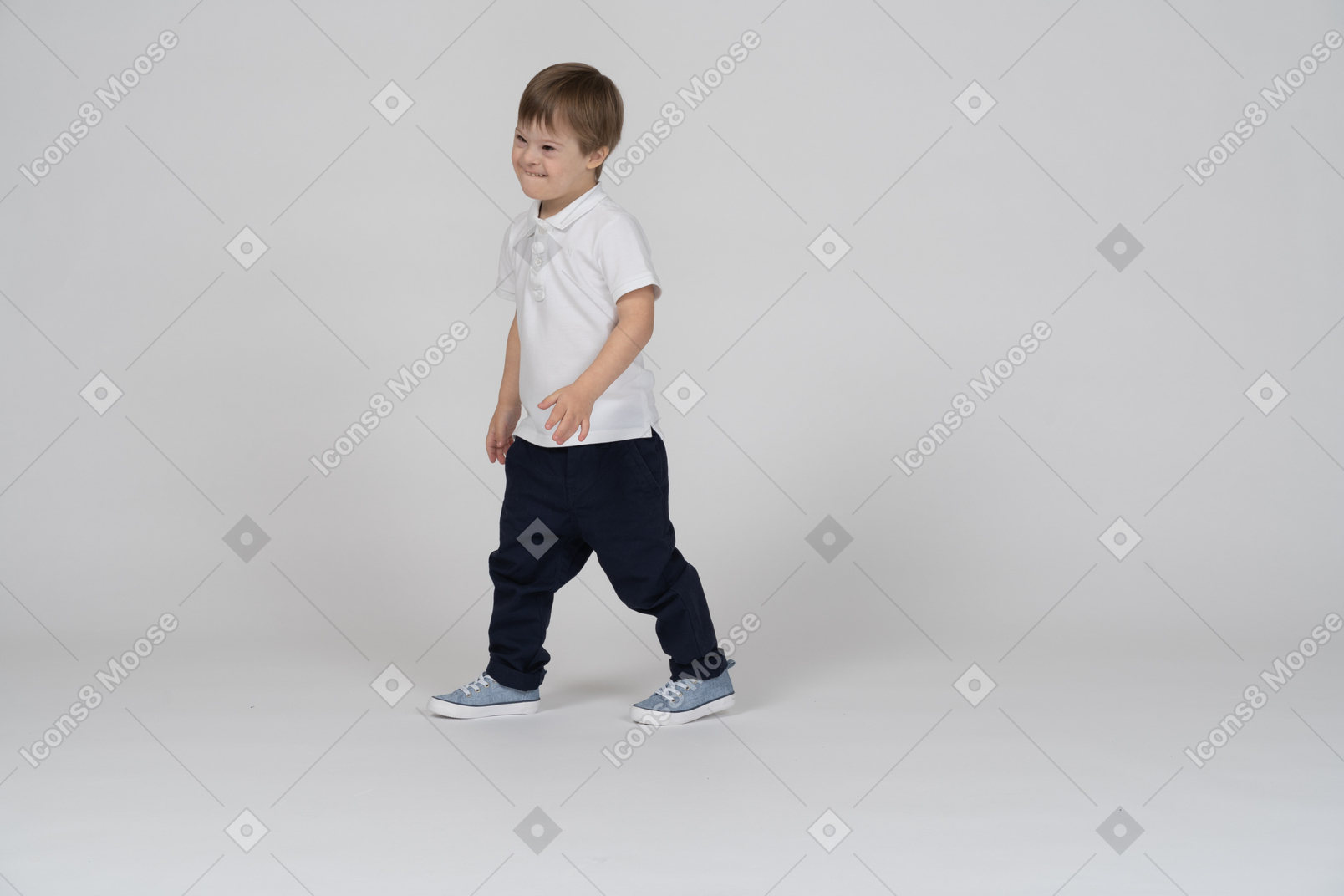 Three-quarter view of a boy walking and biting his lip mischievously