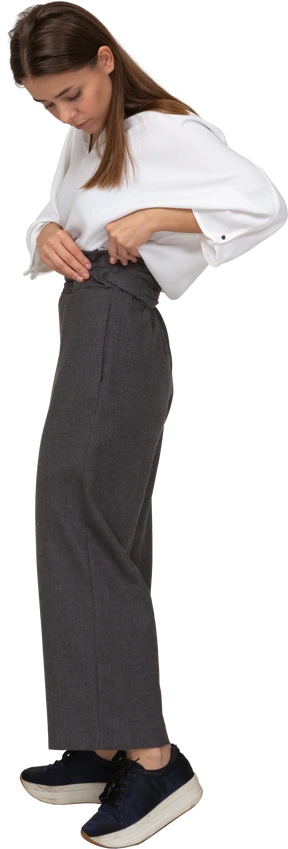 Side view of a young lady in office clothing adjusting her pants
