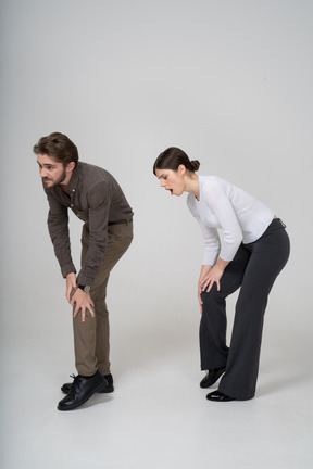 一对穿着办公室服装的年轻夫妇触摸膝盖的四分之三视图