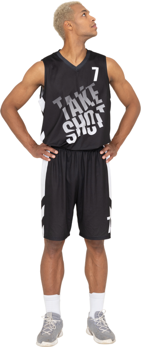 Vue de face d'un jeune joueur de basket-ball masculin mettant les mains sur les hanches et levant les yeux