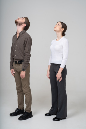 Three-quarter view of a young couple in office clothing looking up