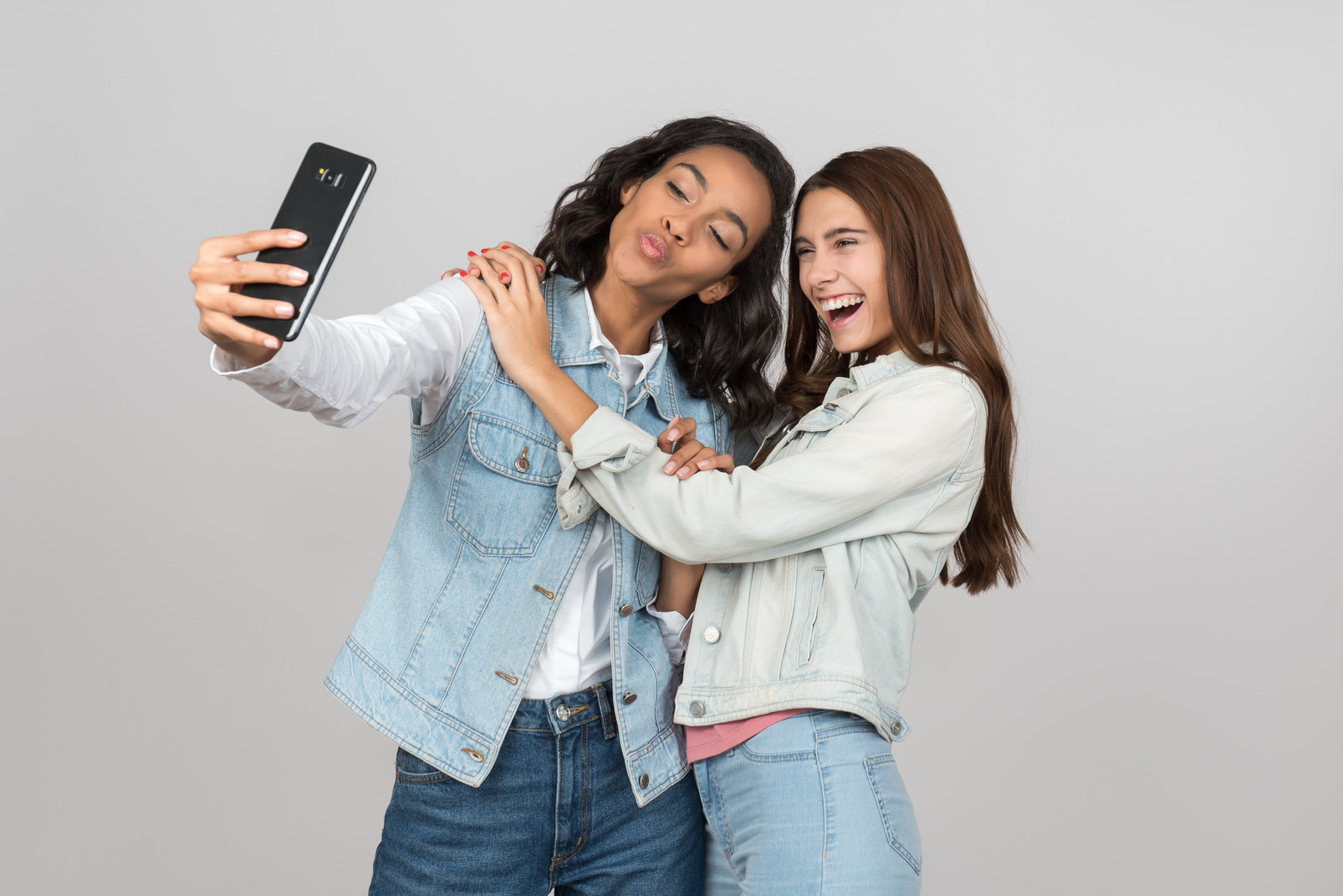 Two young girlfriends making selfies together