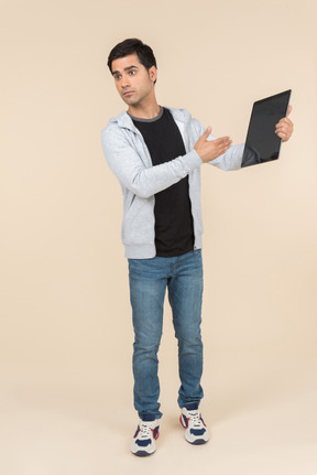 Young caucasian man pointing at a digital tablet he's holding