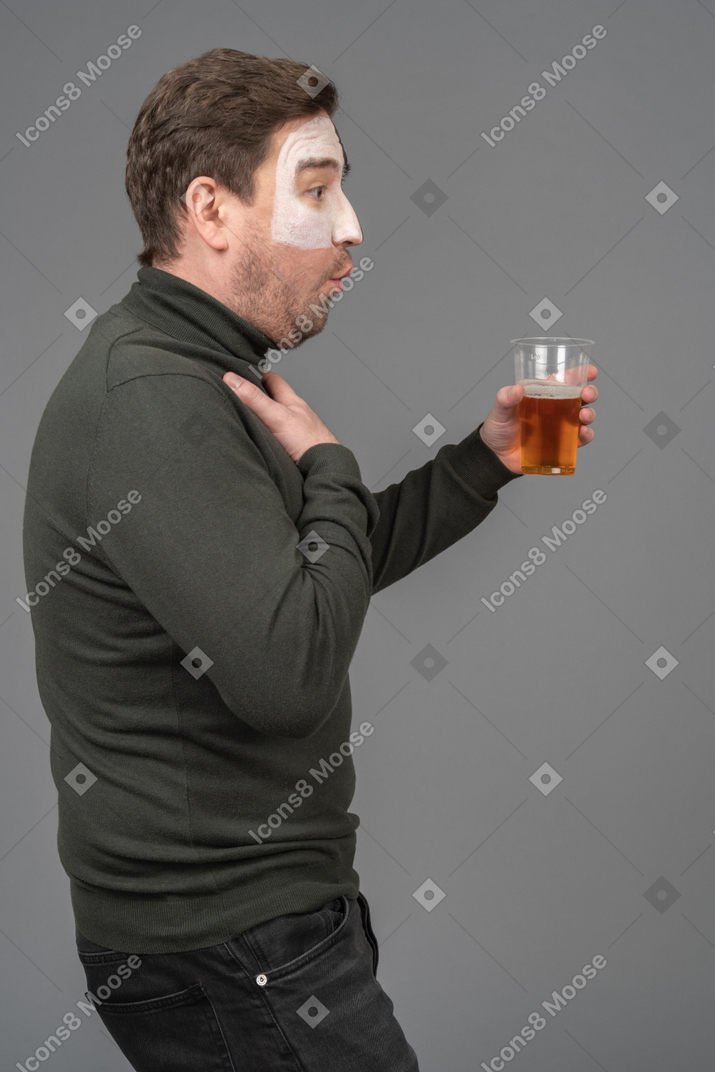 Side view of a surprised male football fan holding a beer