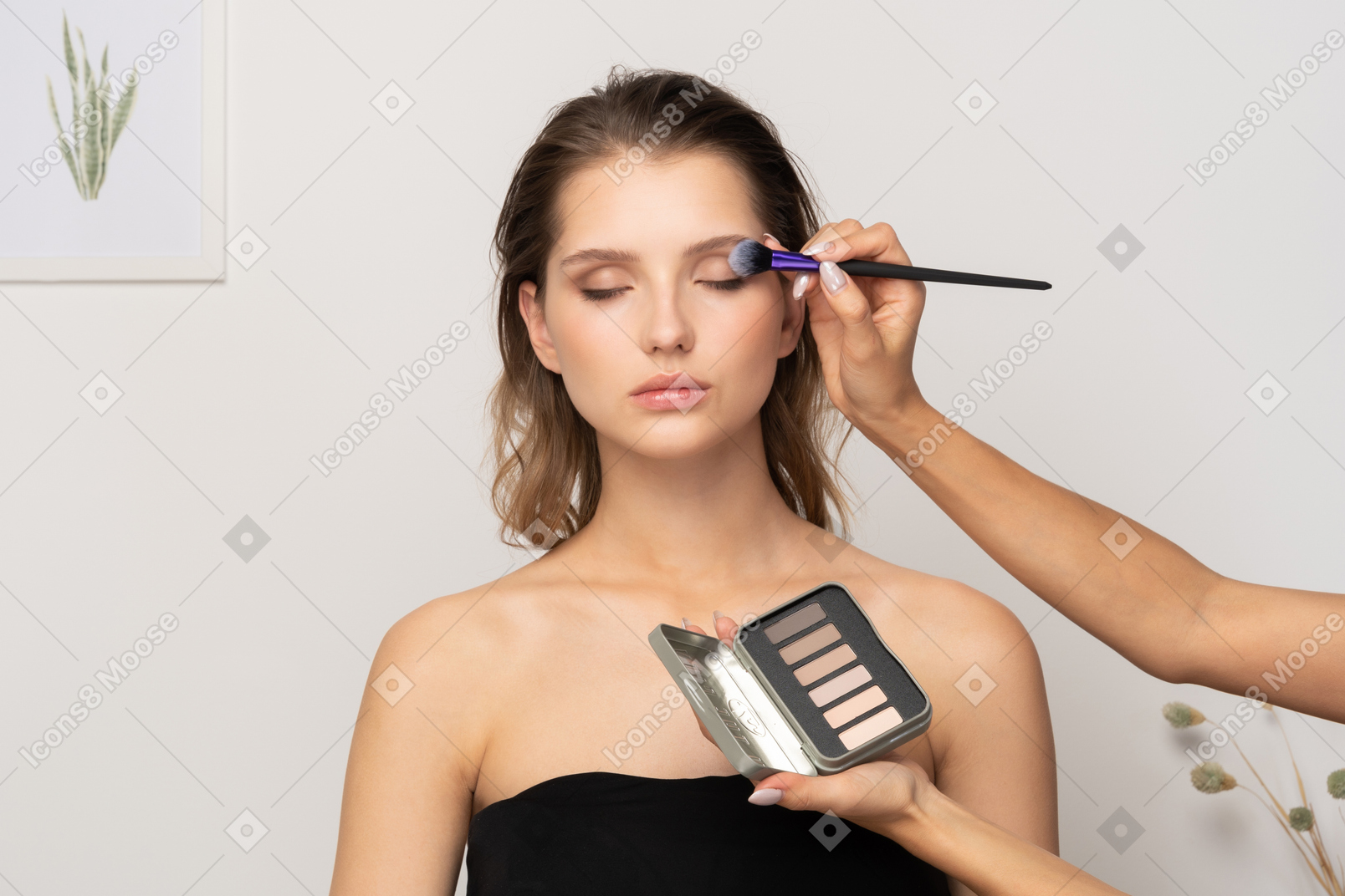 Вид спереди визажиста, делающего макияж глаз женской модели