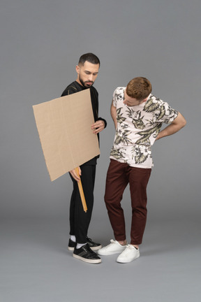 Young men holding and studying a billboard